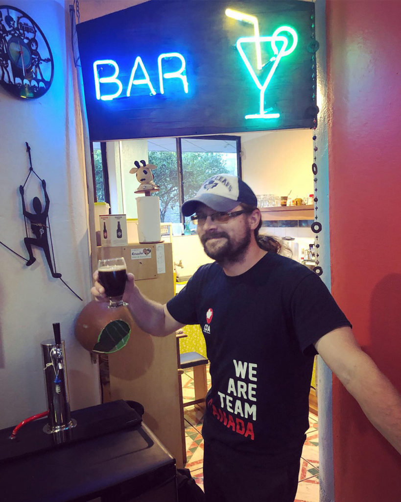 Roger standing under a bar sign in Fauno bar in Cotacachi